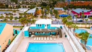 Un hotel con piscina, palmeras y vistas del entorno.