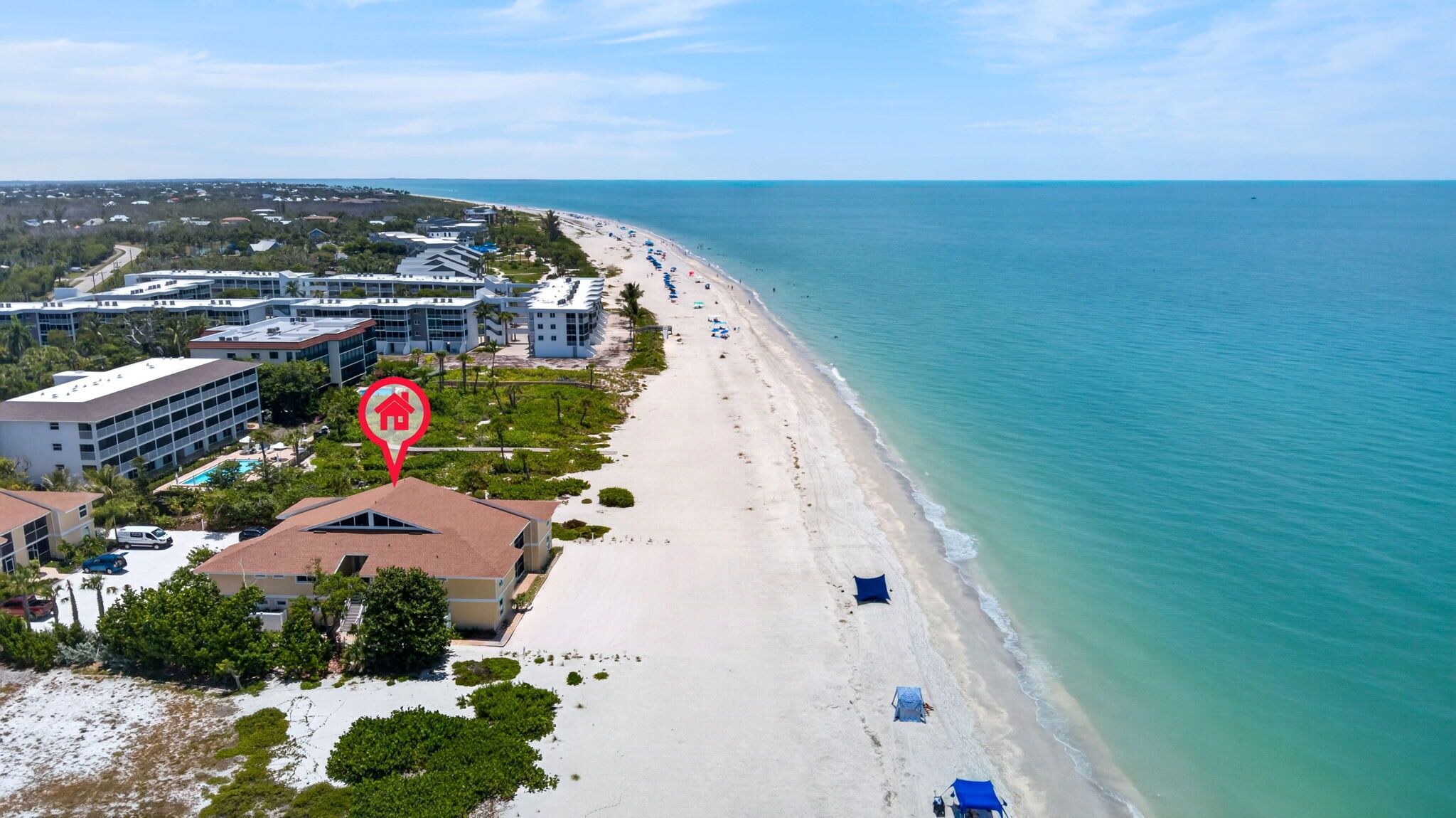 A coastal hotel with a beach view, multiple buildings, and a swimming pool.