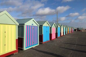 Een rij kleurrijke strandhutten met een heldere lucht op de achtergrond.