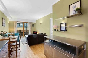 A modern living room with a dining area, a sofa, a TV, and a kitchen counter. - City Belle By My Getaways (Brighton)