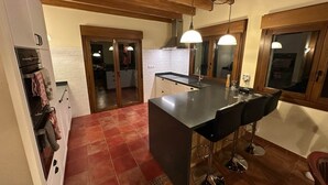 Une cuisine dotée d’un îlot central, de tabourets de bar et d’un plafond en bois.