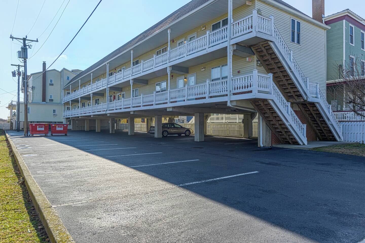 A multi-story motel with a central courtyard, outdoor parking, and a staircase leading to the upper floors.