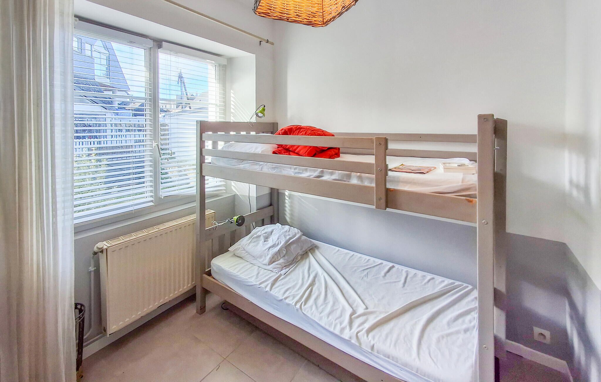 Ein Schlafraum mit Etagenbett, Fenster, Heizkörper und einem kleinen Tisch.