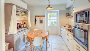 Une cuisine compacte avec une table de salle à manger ronde, des meubles blancs et un four encastré.