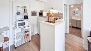 Une cuisine compacte avec des appareils électroménagers blancs, un petit îlot central et un plancher en bois.