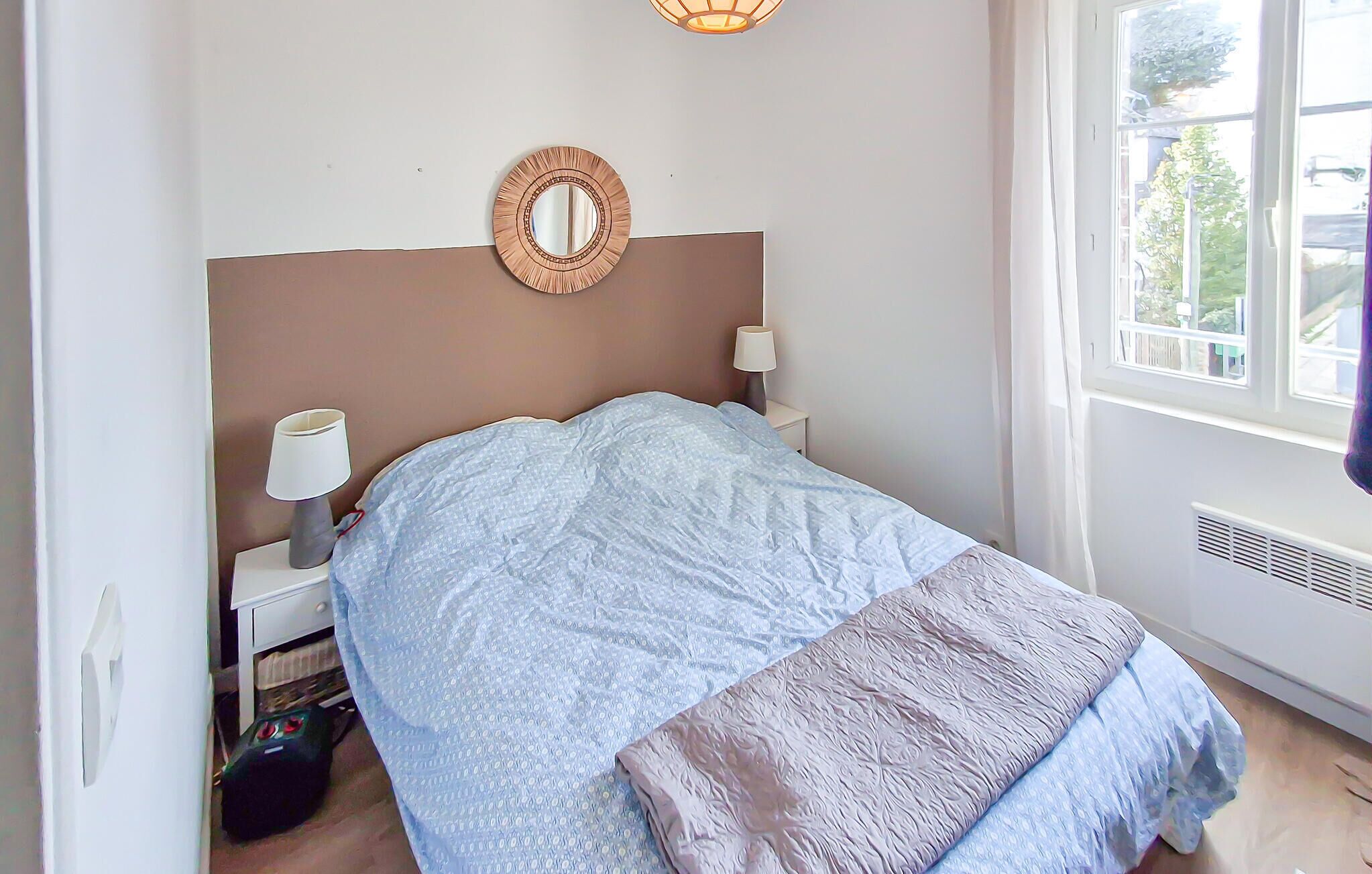 Een slaapkamer met een bed, bedlampen, een spiegel en een raam met uitzicht.