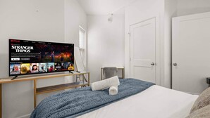 Ett hotellrum med en säng, en tv som visar serien ”Stranger Things” på Netflix, ett litet bord och en dörr.