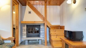 Una habitación acogedora con chimenea de piedra, una escalera de madera y un banco.