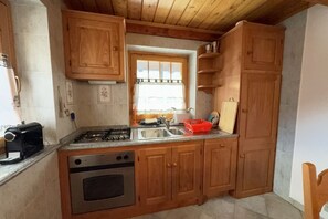 Eine Küche mit Holzausstattung, einem Gasherd, einem Spülbecken und einem Fenster mit Vorhängen.