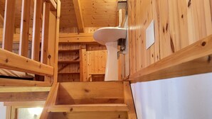 Una escalera de madera con un lavamanos blanco fijado a la pared.