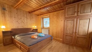 Una habitación con paneles de madera, una cama, mesitas de noche y un ventanal.