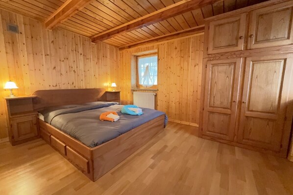 A wooden-paneled room with a bed, nightstands, and a window.
