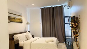 A modern hotel room with a bed, a desk, a chair, a window with curtains, and a decorative plant. - VIP at Embassy Gardens  (Accra)