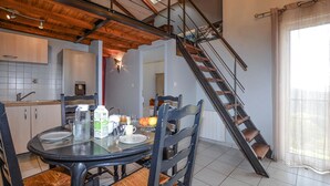 A dining area with a round table, chairs, and a staircase leading to an upper level. - Cozy apartment in Cuttoli with WiFi (Cuttoli)