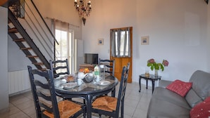A dining area with a round table, chairs, and a chandelier. - Cozy apartment in Cuttoli with WiFi (Cuttoli)