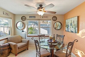 A dining area with a glass table, four chairs, a ceiling fan, and wall decorations including wine-themed signs. - Gulfport Retreat with Wine Cellar Charm (Gulfport)