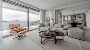 Ein modernes Wohnzimmer mit großem Fenster, einem Ledersessel, einer Couch und einem Essbereich.