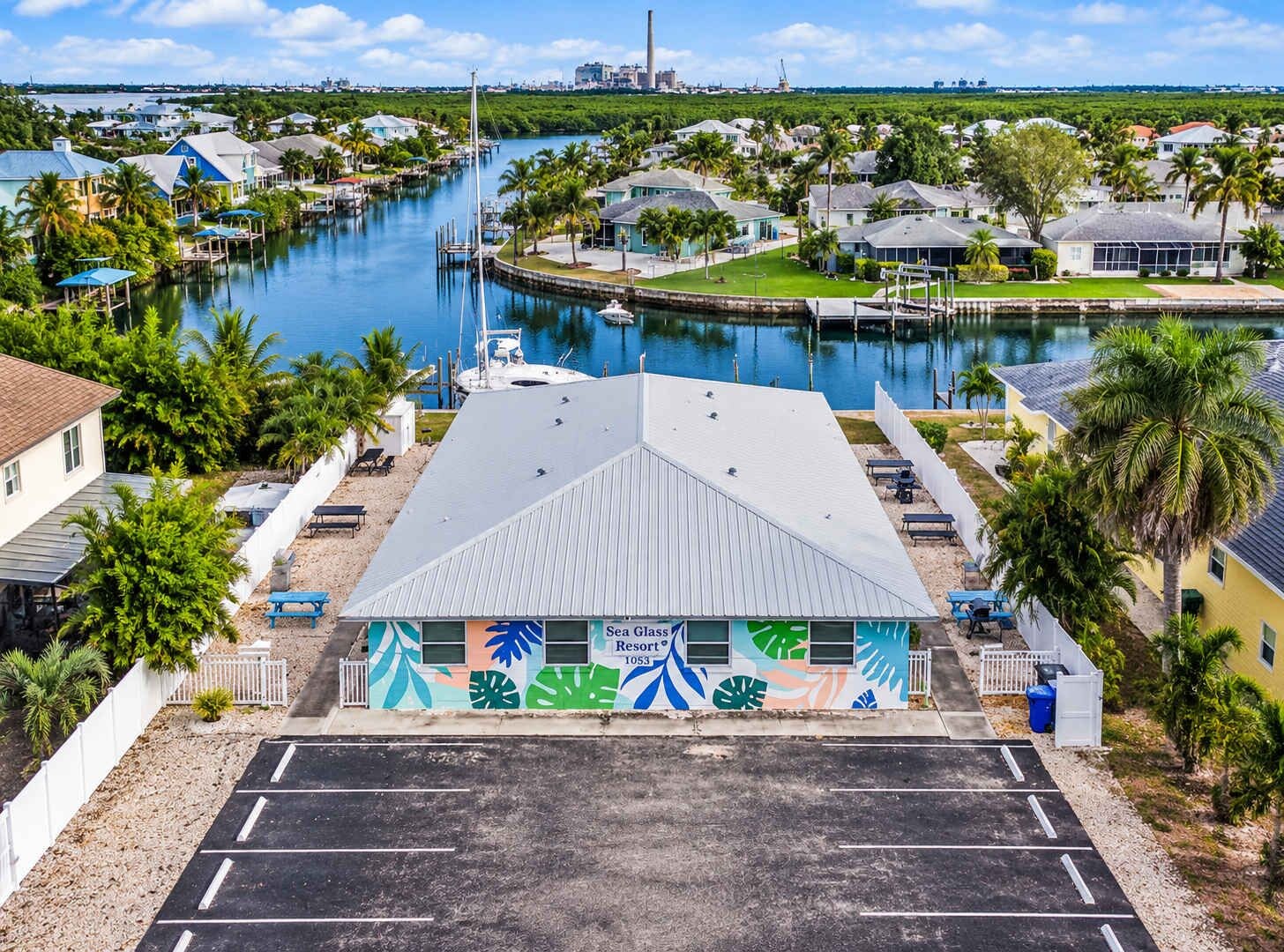 A marina with docked boats, a building with a colorful mural, and a clear view of the water.