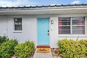 A house with a blue door, a small window with blinds, and a welcome mat with "hello" on it. - Modern Pet-Friendly 2BR Condo (Apollo Beach)