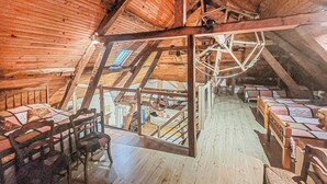 A rustic wooden interior with a high ceiling and exposed beams. There are multiple wooden beds arranged along the walls, and a staircase leads to an upper level. - Beautiful home in Renty with WiFi (Renty)