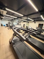 Uma academia com esteiras, equipamentos de ginástica e uma bola de exercício azul.