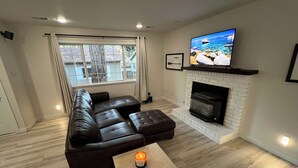 A modern living room with a sectional sofa, a fireplace, a TV mounted above it, and a window with curtains. - Delightful 2-bedroom house in Incline Village near the lake (Incline Village)