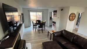 A modern living room with a leather sofa, a TV, and a dining area with chairs and a table. - Delightful 2-bedroom house in Incline Village near the lake (Incline Village)