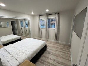 Una camera da letto con due letti, un'ampia finestra con tende, uno specchio e una porta.