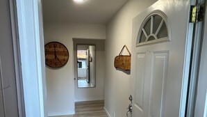 A hallway with a wooden floor, a white door with a window, and a wall clock. - Delightful 2-bedroom house in Incline Village near the lake (Incline Village)