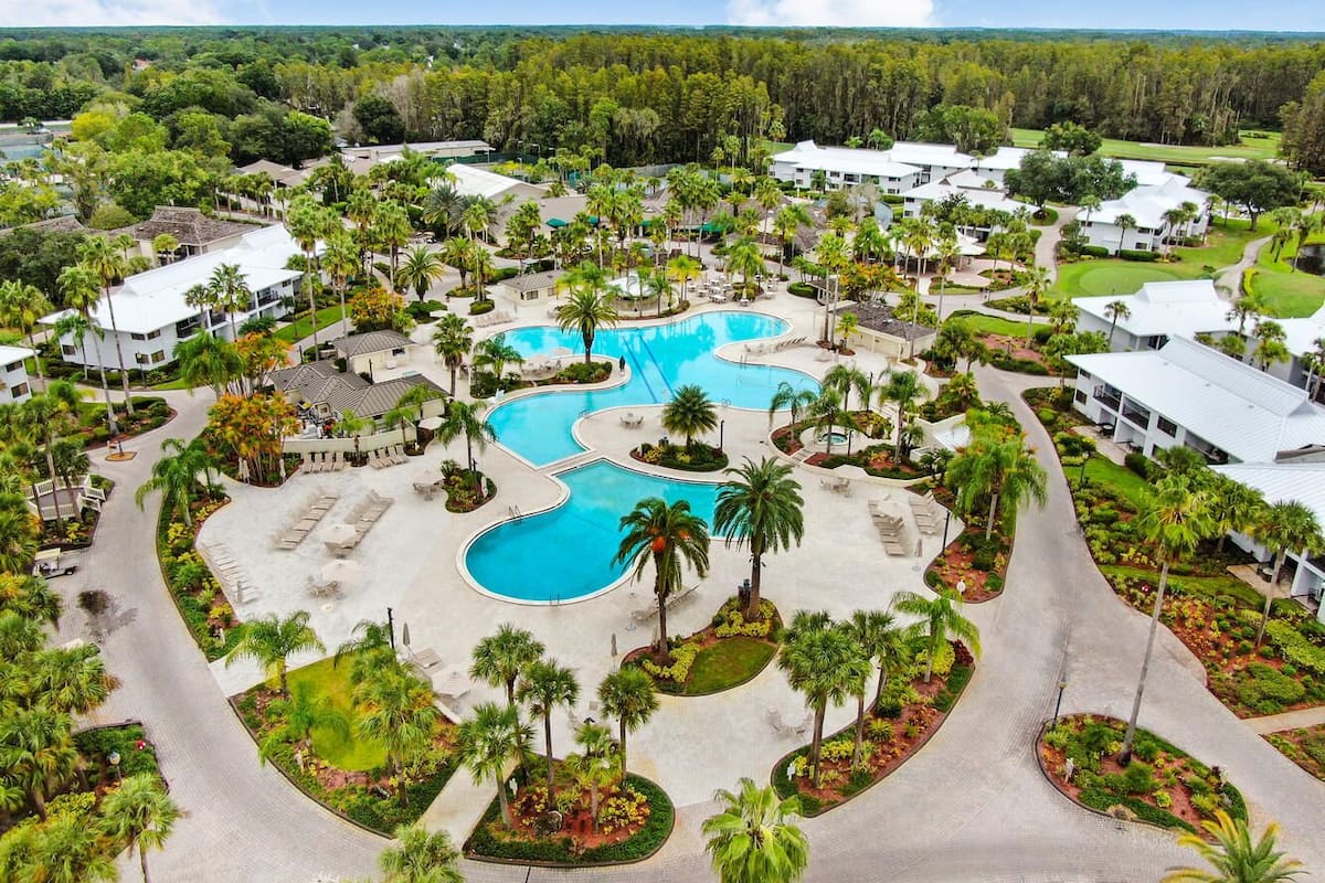 A resort with multiple swimming pools, palm trees, and a golf course.