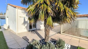 A residential area with a palm tree, a white building with a tiled roof, and a fenced yard. - Stunning home in La Barre de Monts (La Barre de Monts)