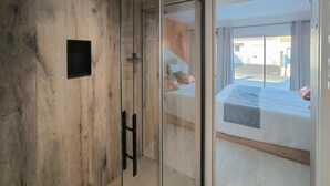 A room with a wooden wall, a sliding glass door leading to a balcony with a bed and pillows. - Stunning home in La Barre de Monts (La Barre de Monts)