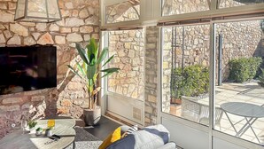 A cozy living room with a stone wall, a large window, a flat-screen TV, and a potted plant. - Lovely home in Les Arcs with private swimming pool, can be inside or outside (Les Arcs)