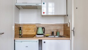 A compact kitchen with a built-in dishwasher, a kettle, and a coffee maker. - Urszula, charmant studio proche du Vieux Marché (Rouen)
