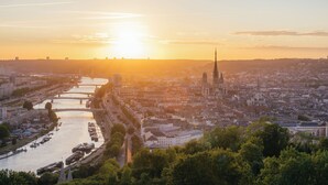 A cityscape with a prominent tower, a river, and a bridge during sunset. - Urszula, charmant studio proche du Vieux Marché (Rouen)