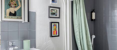 A bathroom with a white sink, a framed poster, a shower curtain, and a toilet.