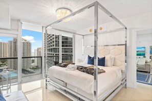 A modern bedroom with a glass canopy bed, a city view, and a balcony with a pool.