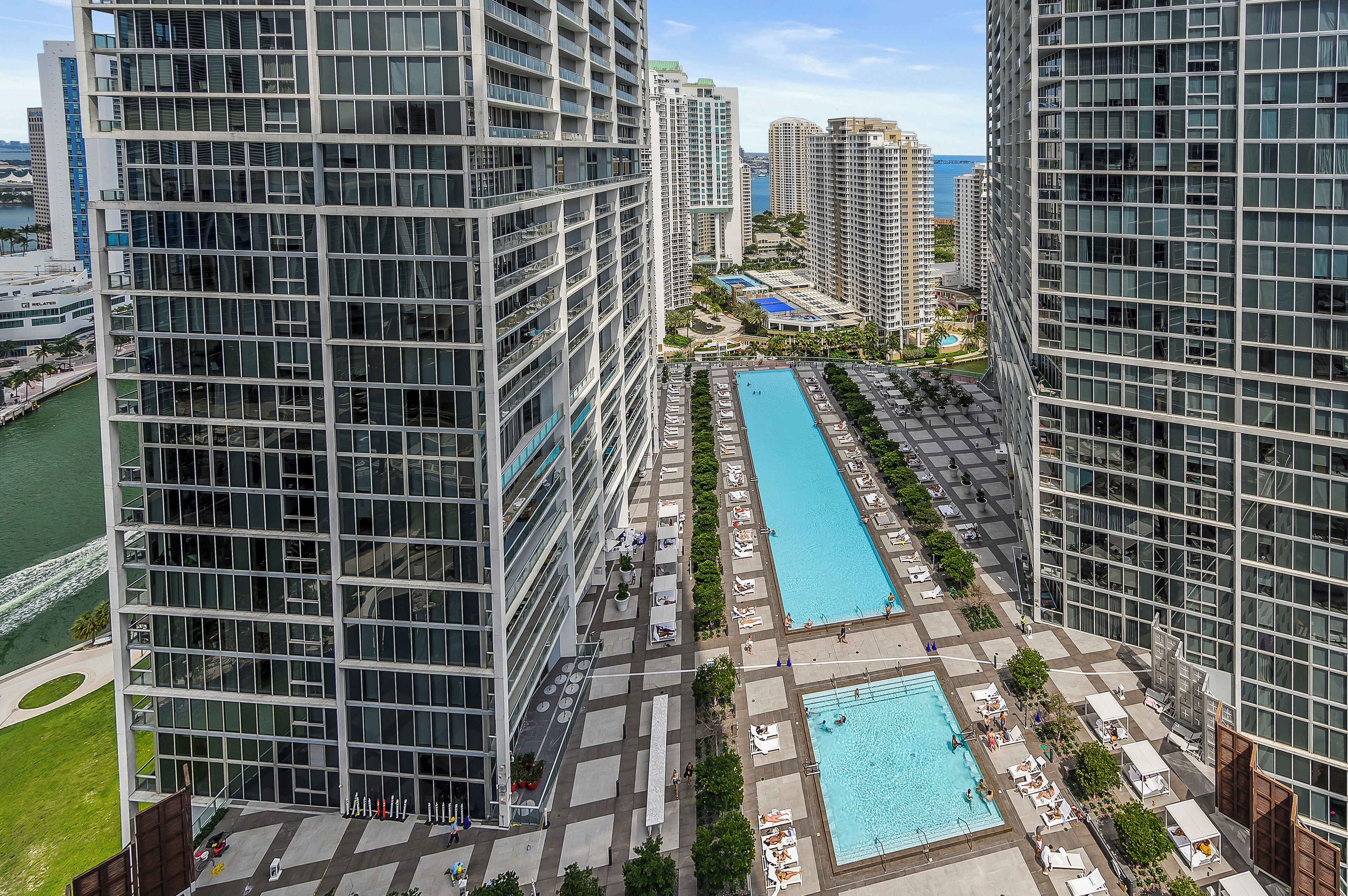 A high-rise building with a rooftop pool and lounge area, surrounded by other tall buildings.