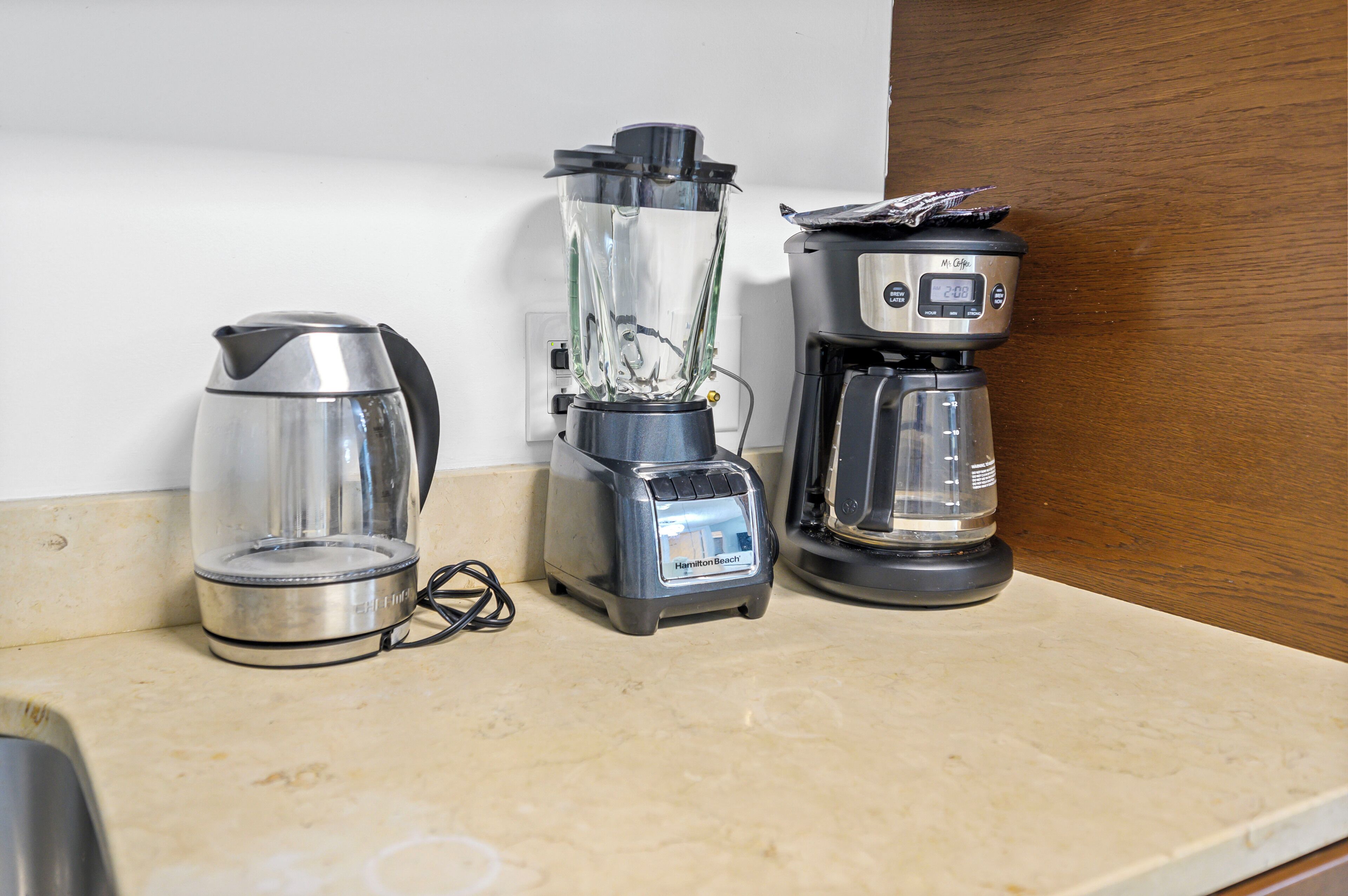 Un plan de travail de cuisine avec une machine à café, un mixeur et une bouilloire.