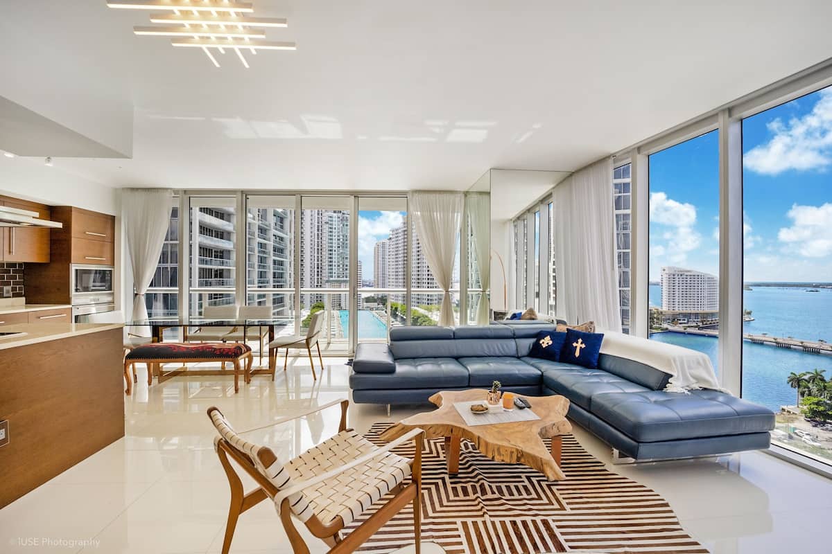 A modern living room with a blue sofa, a wooden coffee table, and a view of the sea.