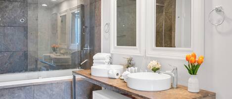Un baño moderno con ducha acristalada, tocador doble y un espejo grande.