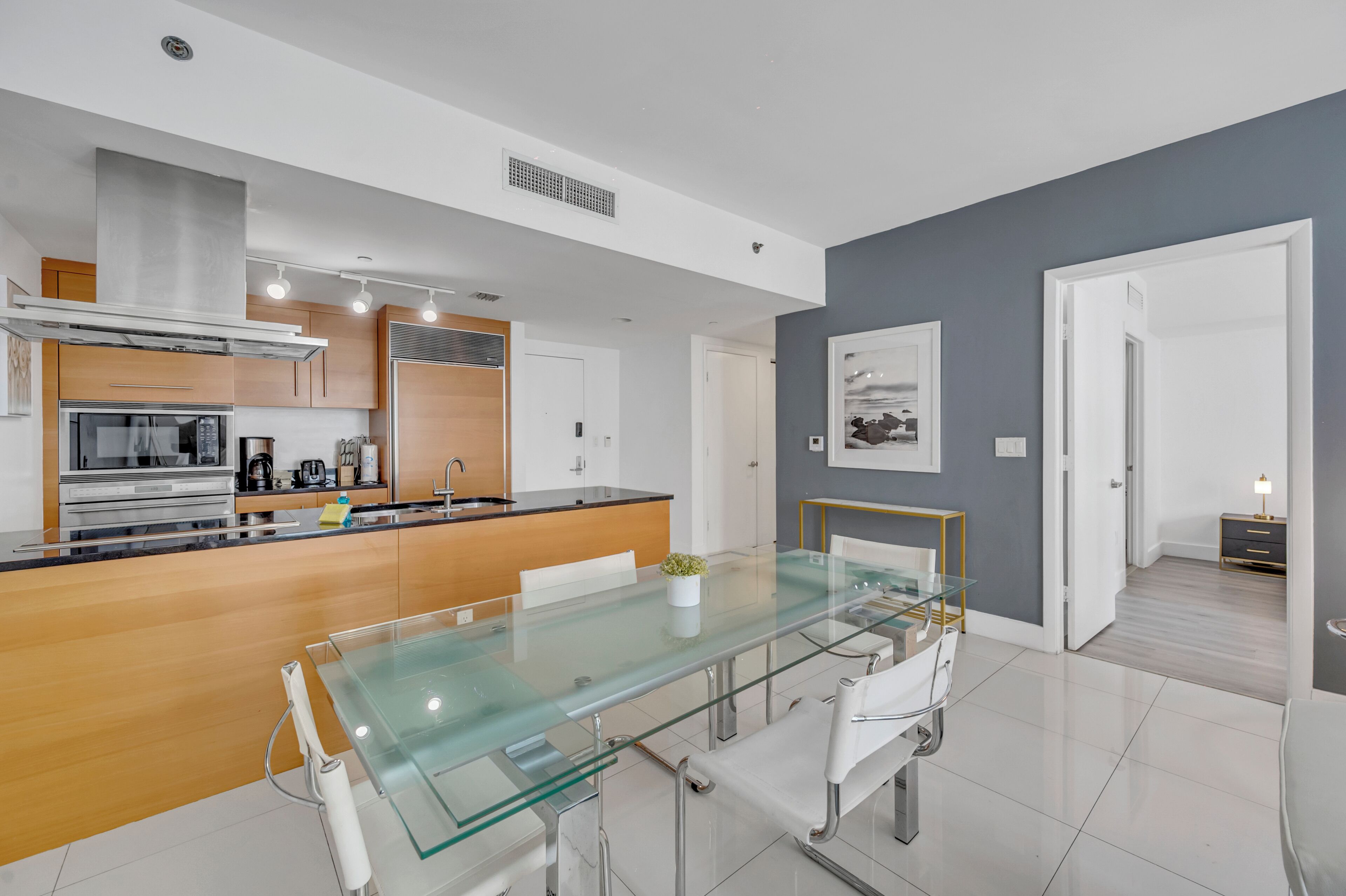 A modern kitchen with stainless steel appliances, a glass dining table, and a minimalist design.
