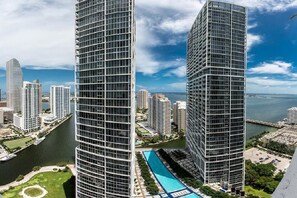 A high-rise building with a modern glass facade, surrounded by other high-rise buildings and a body of water.