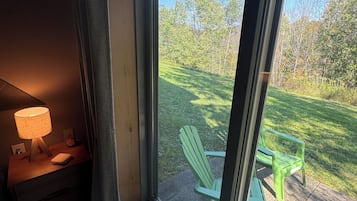 A room with a large window, a green chair, and a table outside.