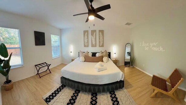 Une chambre moderne avec un grand lit, un ventilateur de plafond et une vue sur l’extérieur.