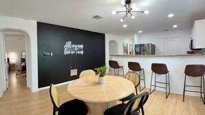 Une cuisine moderne avec des meubles blancs, un îlot central et un coin repas comprenant une table ronde et des chaises.