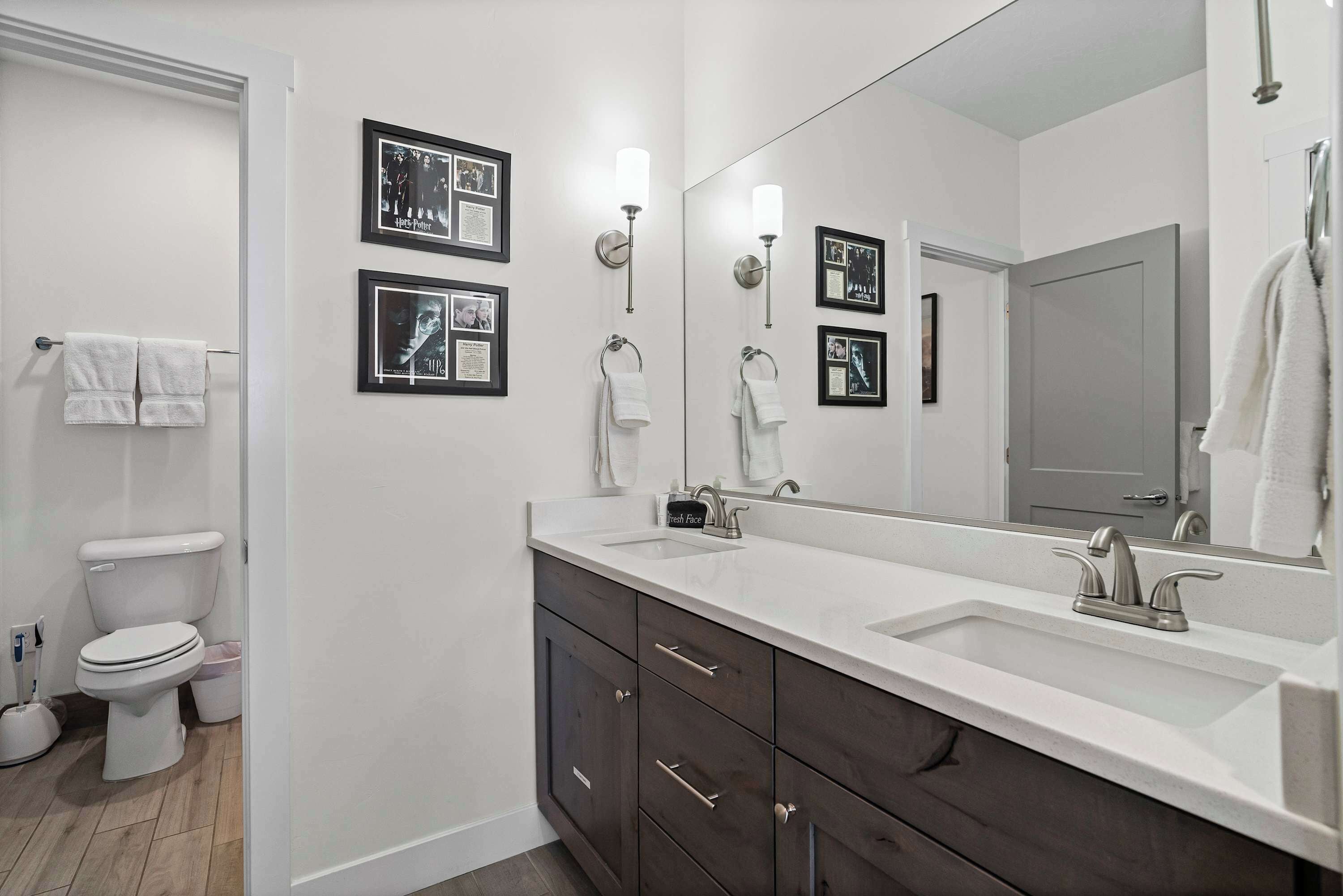 A modern bathroom with a white sink, dark cabinets, and a large mirror.
