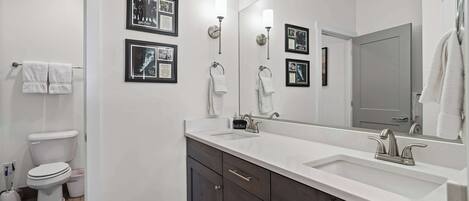 A modern bathroom with a white sink, dark cabinets, and a large mirror.