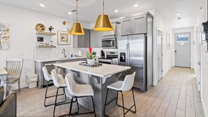A modern kitchen with a central island, stainless steel appliances, and pendant lighting. - The Show House - Retreat for 10 (Washington)