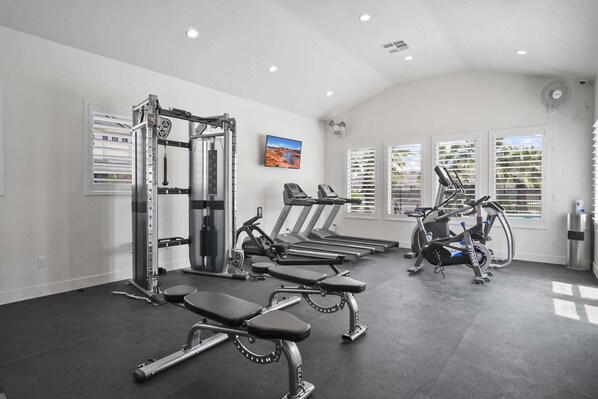 Une salle de sport équipée de tapis de course, de vélos elliptiques et de matériel de musculation.
